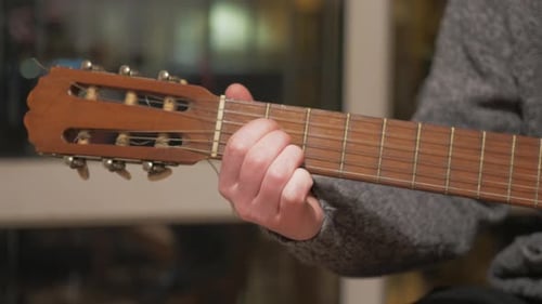 Man plays the acoustic guitar fingerboard and frets Close-up