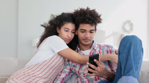 Loving Couple Relaxing at Home with a Mobile Phone