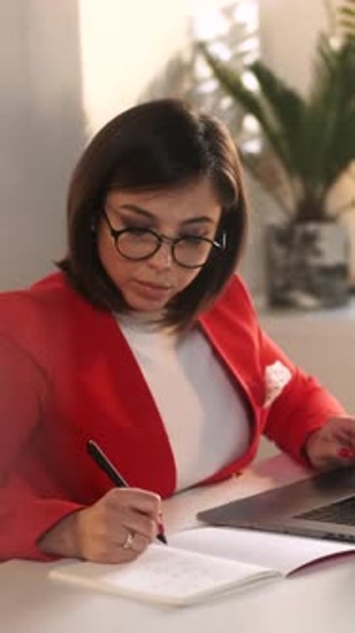 Woman Working at Home Office with Laptop and Notebook