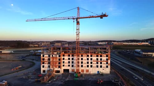 Vista aérea del sitio de construcción con grúa bajo el anochecer o el amanecer iluminado por la luna