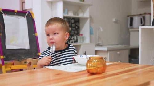 Little One Eating at Kitchen Table with Spoon in Cozy Home