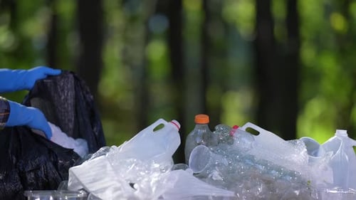 Gloved Hands Sorting Plastic Waste into Garbage Bag