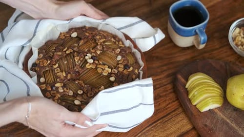 close-up woman puts hot fresh cupcake with fruits and nuts on the table