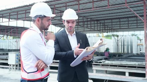 Construction Site: Engineers Reviewing Blueprints and Communicating