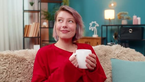 Smiling woman drinking from a mug on sofa