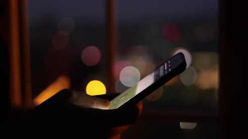 Hand Using Smartphone at Night with Bokeh