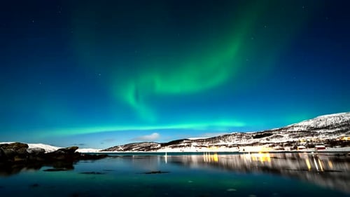 Home lights and dreamlike aurora borealis reflected in Skogsfjord, time-lapse