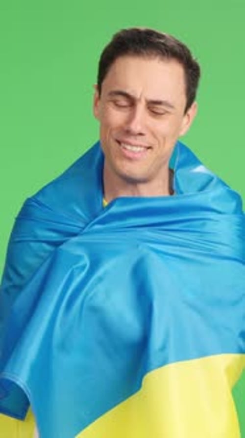 Man draped in flag poses against green screen