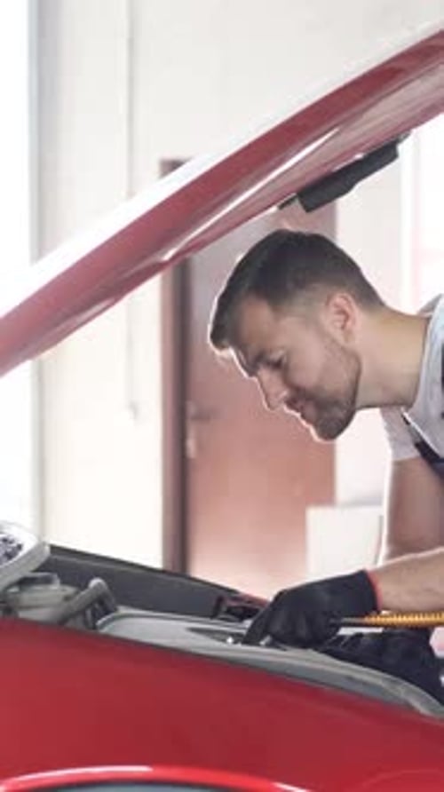 A Professional Car Mechanic Examines a Car at a Car Service Performing a Series of Tests