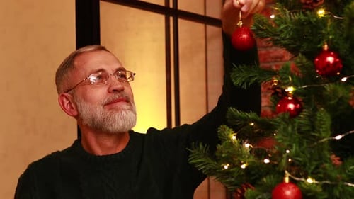 an Elderly Man in a Green Knitted Decorating the Christmas Tree