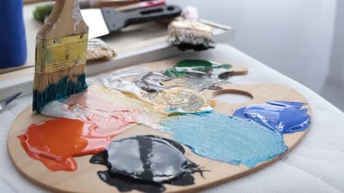 Mélanger avec un pinceau épais des peintures acryliques sur une palette
