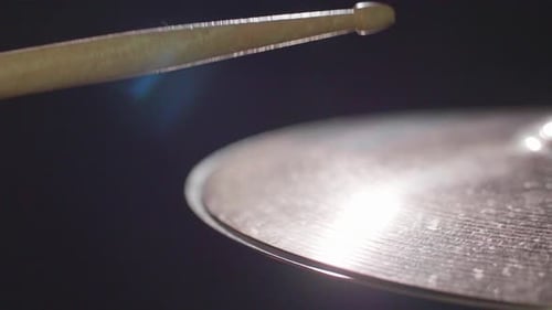 Smooth close up of a shiny drum hi-hat being played with sticks. Super Close up with a dark backgrou