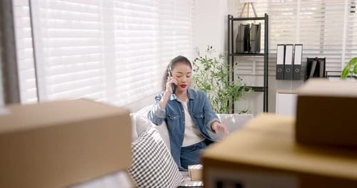 Young Woman on Phone Holding Box in Living Room
