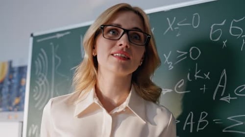 College Teacher Teaching Class Showing Physics Formulas on Blackboard Closeup