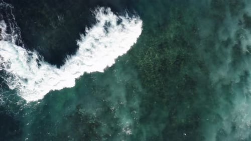 Meereswellen, die über das Riff fließen, auf klarem Blauwasser, aufgenommen mit einer Luftdrohne