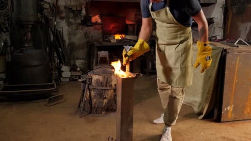 Man Torching Metal in Blacksmith Workshop