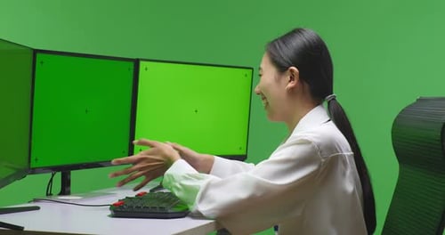 Seitenansicht einer asiatischen Frau beim Video mit einem nachgebildeten Computerbildschirm im Greenscreen-Studio