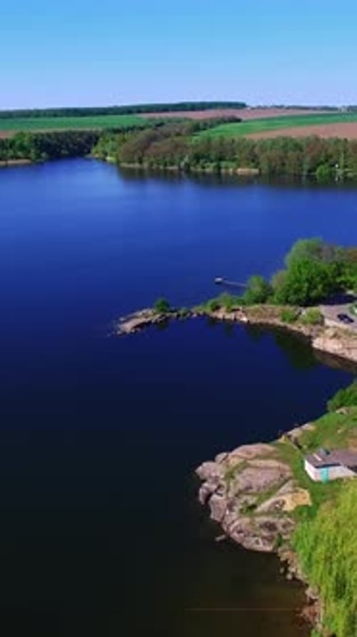 Automobile road with some cars at the waterfront. Drone flying over the azure river on sunny day