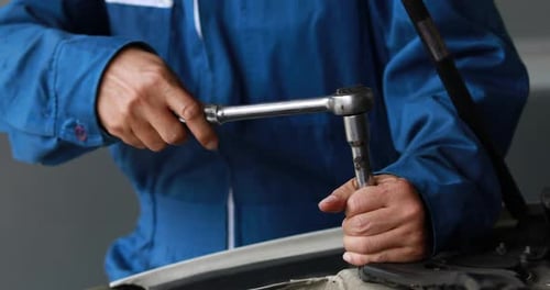 Male mechanic repairs car in garage. Car maintenance and auto service garage concept.