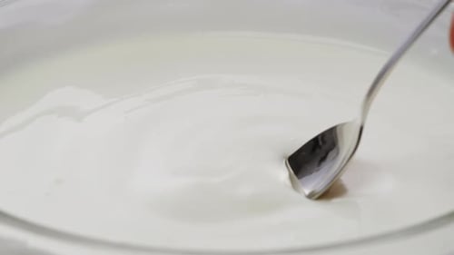 White Creamy Sauce Texture Closeup Dip a Spoon Into White Yogurt Macro Dairy Products Concept