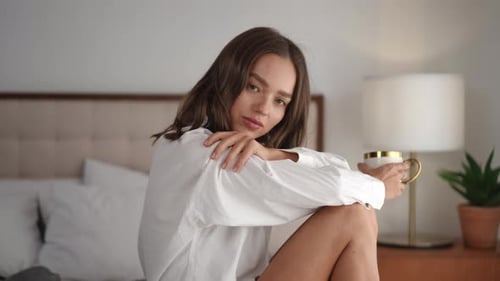 Beautiful Young Woman Drinking Morning Coffee in Bed