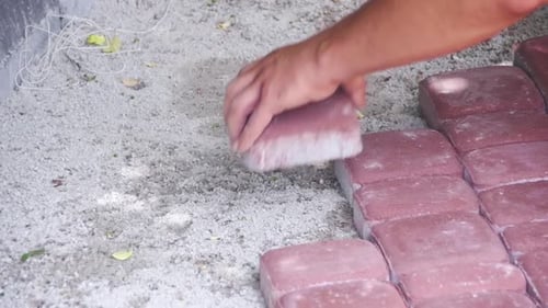 Un trabajador coloca adoquines con un martillo en cámara lenta
