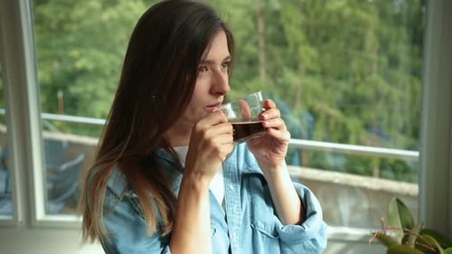 Woman Drinking Coffee by the Window at Home