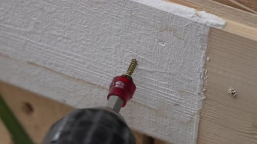 A Man Hands Using a Power Tool Fastens a Board with a Screw Slow Motion
