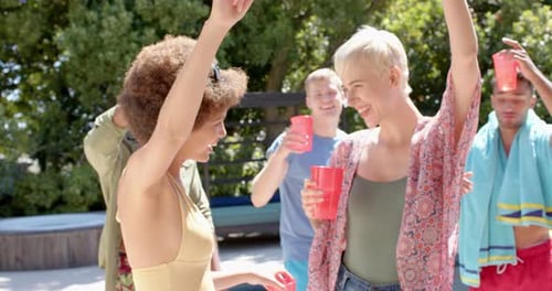 Happy diverse group of friends having barbecue and dancing at pool party in summer