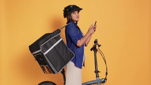 Delivery Worker Stands with Bicycle Checking Phone