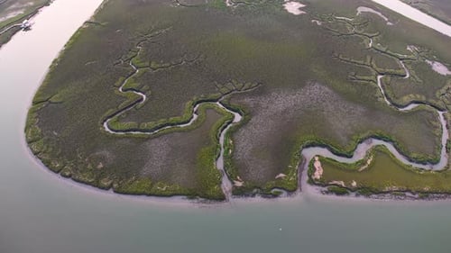 Aerial view of a small island with twisting tidal creeks surrounded by coastal marshland at sunset