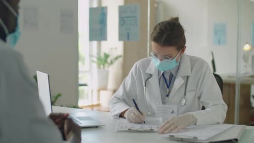 Female Doctor in Mask Consulting Patient in Clinic