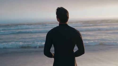 Young Adult in Wetsuit on Beach at Sunrise