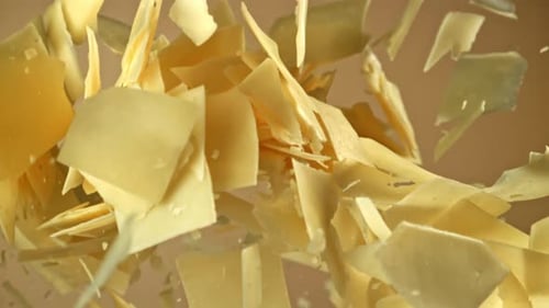 Queso parmesano en cámara lenta sobre un fondo claro filmado con una cámara de alta velocidad a 1000 fps