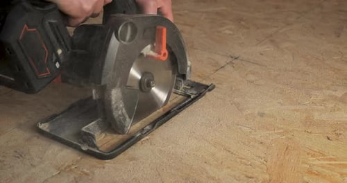 Closeup of a Worker Using a Circular Saw to Cut Plywood
