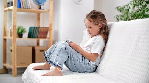 Girl Using Mobile Phone on Couch at Home