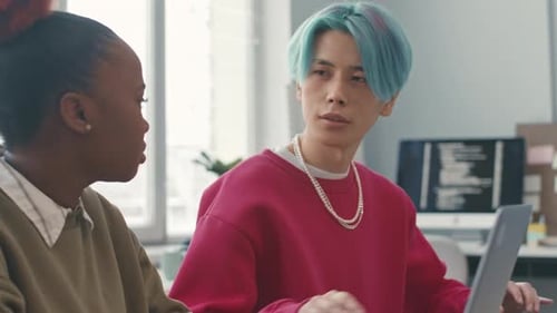 Une programmeuse asiatique discute avec une collègue au travail