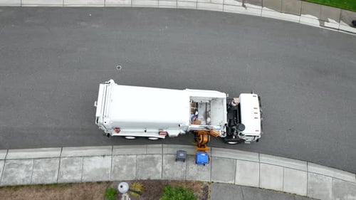 Top down view of a waste facilities truck as it loads recycling from the curb into its payload.