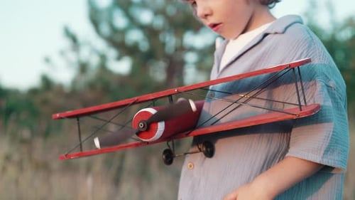 Un curioso niño preescolar de 5 años juega a manualidades con un avión de madera de estilo retro