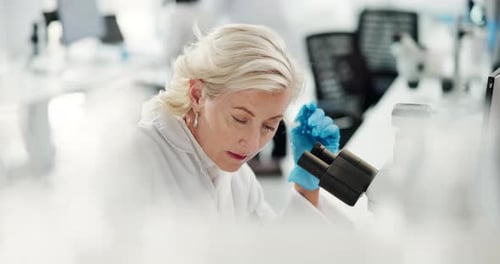 Focused Scientist Viewing Sample Through Microscope in Lab