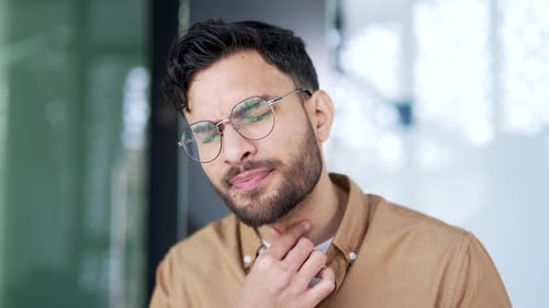 A sick businessman suffering from a sore throat while sitting at a workplace in a business office.