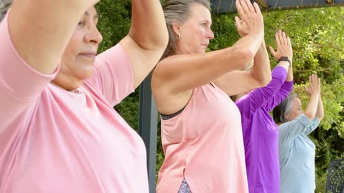 Diverse Group of Mature Women Practicing Yoga Outdoors in a Lush Garden