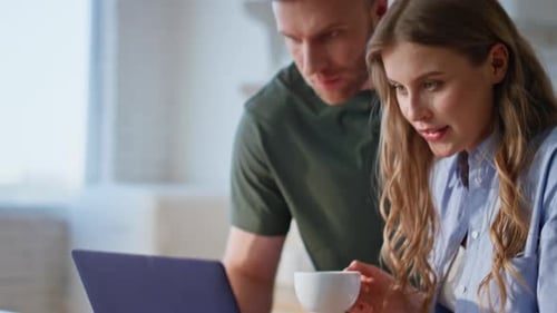 Woman Typing on Laptop with Man in Kitchen