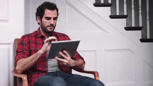 Man Relaxing in Chair Using Tablet Device