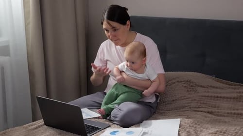 Caucasian Mother Tutoring Via Laptop While Holding Baby Animated Gestures And Clear Explanations