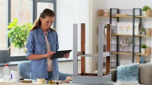 Woman Uses Tablet While Painting Refurbished Chair
