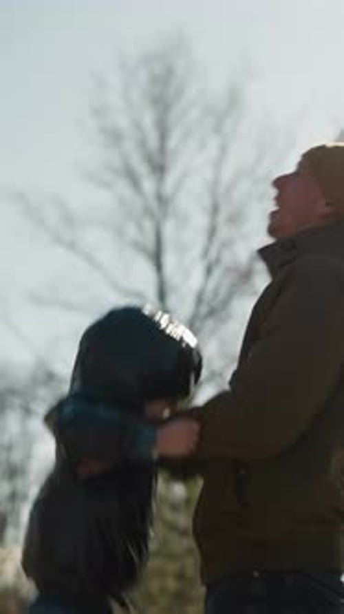 Joyful Father Lifting Child Outdoors Side View with Clear Sky