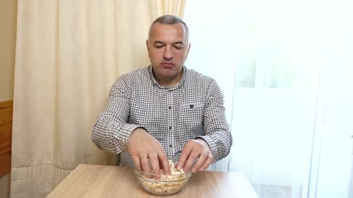 Man Enjoys Bowl of Popcorn Snack at Table