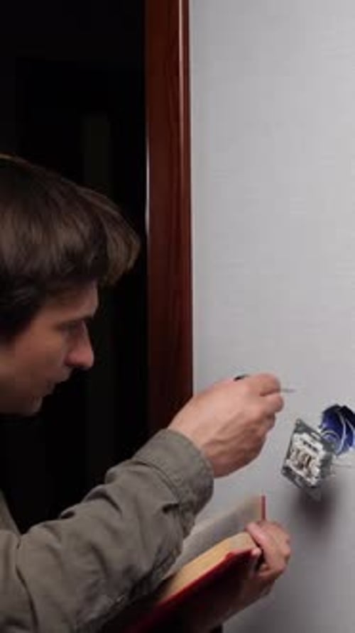 Man Repairs Electrical Socket at Home Using Book