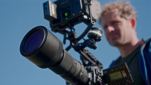 Professional Video Camera with Large Lens Against Sky